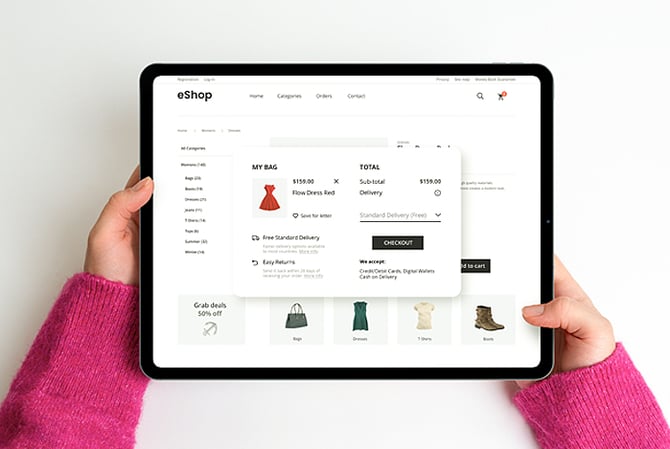 Mercado Pago: braços segurando um tablet visto de cima com a tela no checkout de pagamento de um e-commerce de roupas.