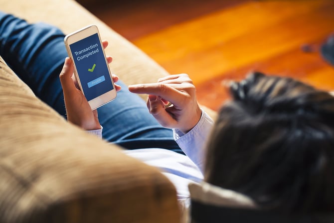 Empreendedora deitada em sofá de sala segurando celular em tela de pagamento aprendendo como cobrar com link de pagamento