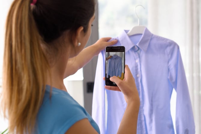 Mercado Pago: mulher fotografando com um celular uma camisa em um cabide para vender no seu brechó online