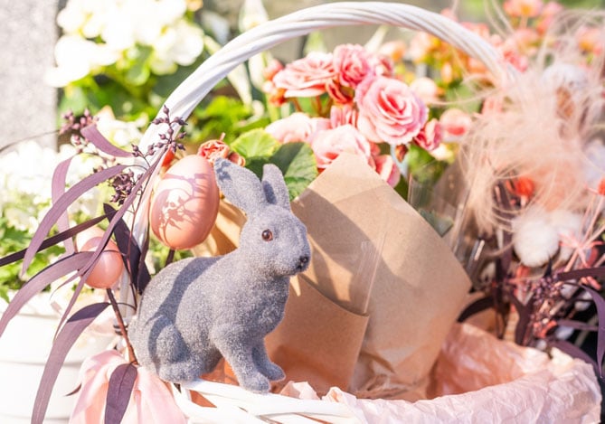 Mercado Pago: imagem de uma cesta de Páscoa com mix de produtos, enfeitada com rosas cor de rosa e um coelho cinza, ilustrando um produto que teria sido confeccionado para venda na Páscoa 2025.