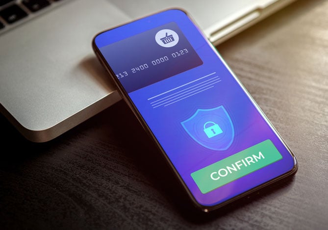 Mercado Pago: celular apoiado em um notebook com foco na tela, onde tem um sistema de pagamento de uma loja online aberto pedindo para finalizar a compra. 