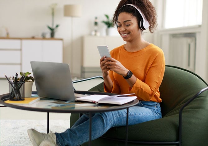 Mulher com celular nas mão em frente ao computador