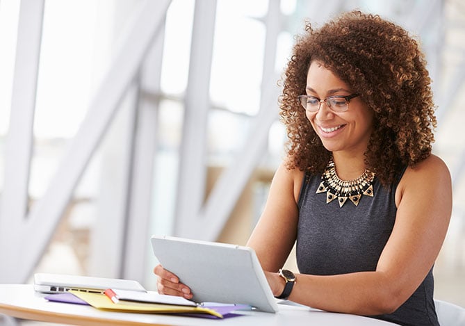 Mulher sorrindo e mexendo no tablet analisando crediário Mercado Pago