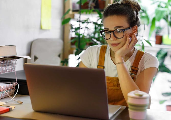 Mulher em frente ao computador com um dos braços apoiados na mesa