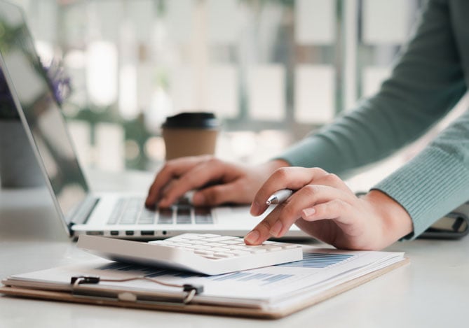 Mercado Pago: empreendedora calculando o preço de revenda de produtos em seu notebook.