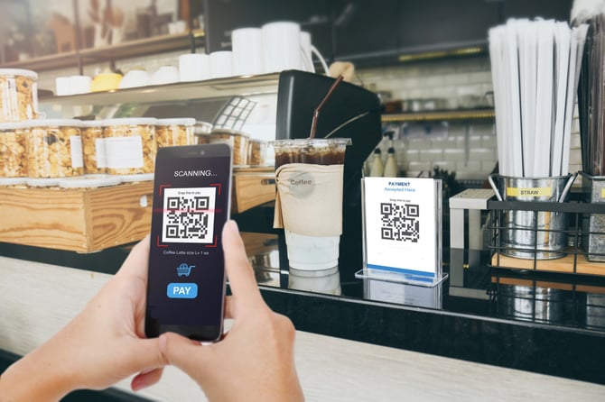 Mão de empreendedor segurando celular e escaneando código QR e link de pagamento Mercado Pago
