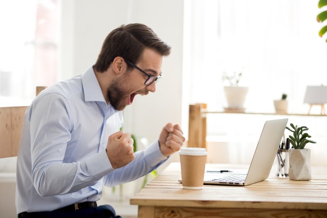 Mercado Pago: empreendedor em sua mesa de trabalho em frente ao seu notebook comemorando seu e-commerce de sucesso