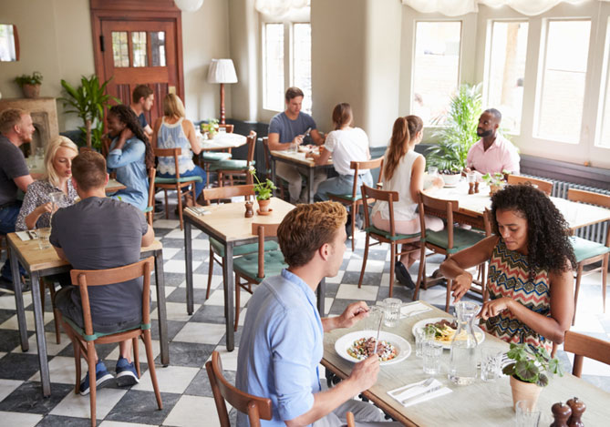 Mercado Pago: imagem de pessoas sentadas em diversas mesas de um restaurante do segmento de alimentação saudável fazendo uma refeição.