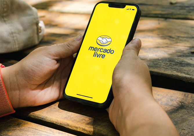 Mercado Pago: mãos de uma pessoa segurando um smartphone com a tela ligada aparecendo o logo do maior marketplace da América Latina sugerindo como vender pelo Mercado Livre