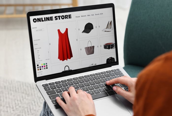 Mercado Pago: pessoa vista de cima com notebook no colo, programando uma loja de roupas online de forma estratégica para evitar a desistência de compra. 
