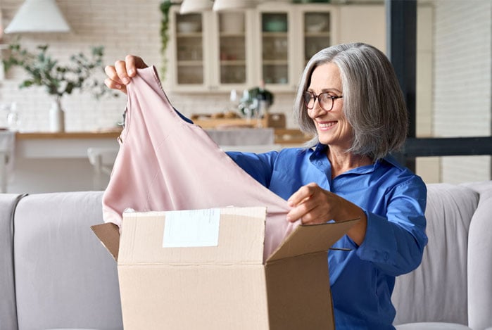 Mercado Pado: mulher tirando uma camiseta de uma caixa vinda de uma compra de dropshipping de roupas que ela fez