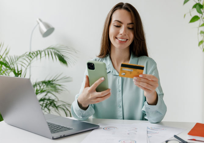 Empreendedora em mesa de trabalho com notebook, celular e cartão realizando vendas com o Link de Pagamento Mercado Pago
