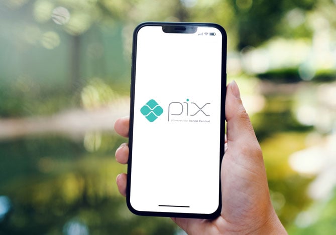 Mercado Pago: mão segurando um smartphone com o símbolo do Pix por aproximação aberto na tela.