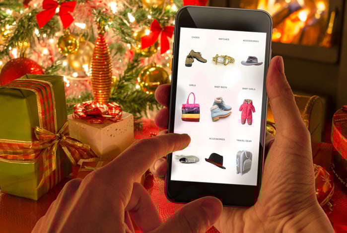 Mercado Pago: mãos segurando um celular na frente de uma árvore natalina. A tela está aberta em um e-commerce com promoções de Natal. 