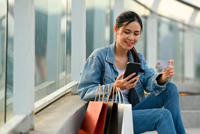 Mercado Pago: mulher sentada na calçada acompanhando as tendências de consumo