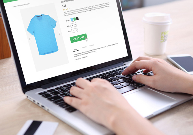 Mãos de uma pessoa usando um laptop para comprar uma camiseta em um e-commerce que realiza vendas online com o Mercado Pago.