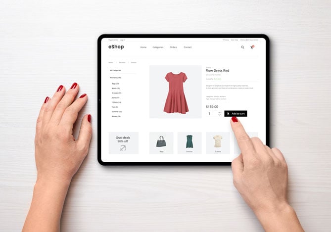 Mercado Pago: mãos de uma mulher com unhas pintadas de vermelho mexendo em um tablet, que está com a tela ligada em um e-commerce de roupas, podendo se deparar com vendas sem estoque.