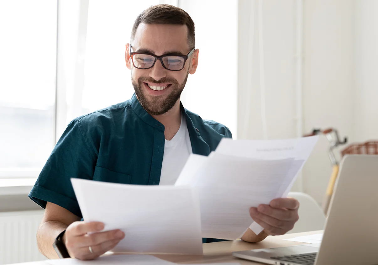 Homem de óculos sorrindo enquanto analisa documentos