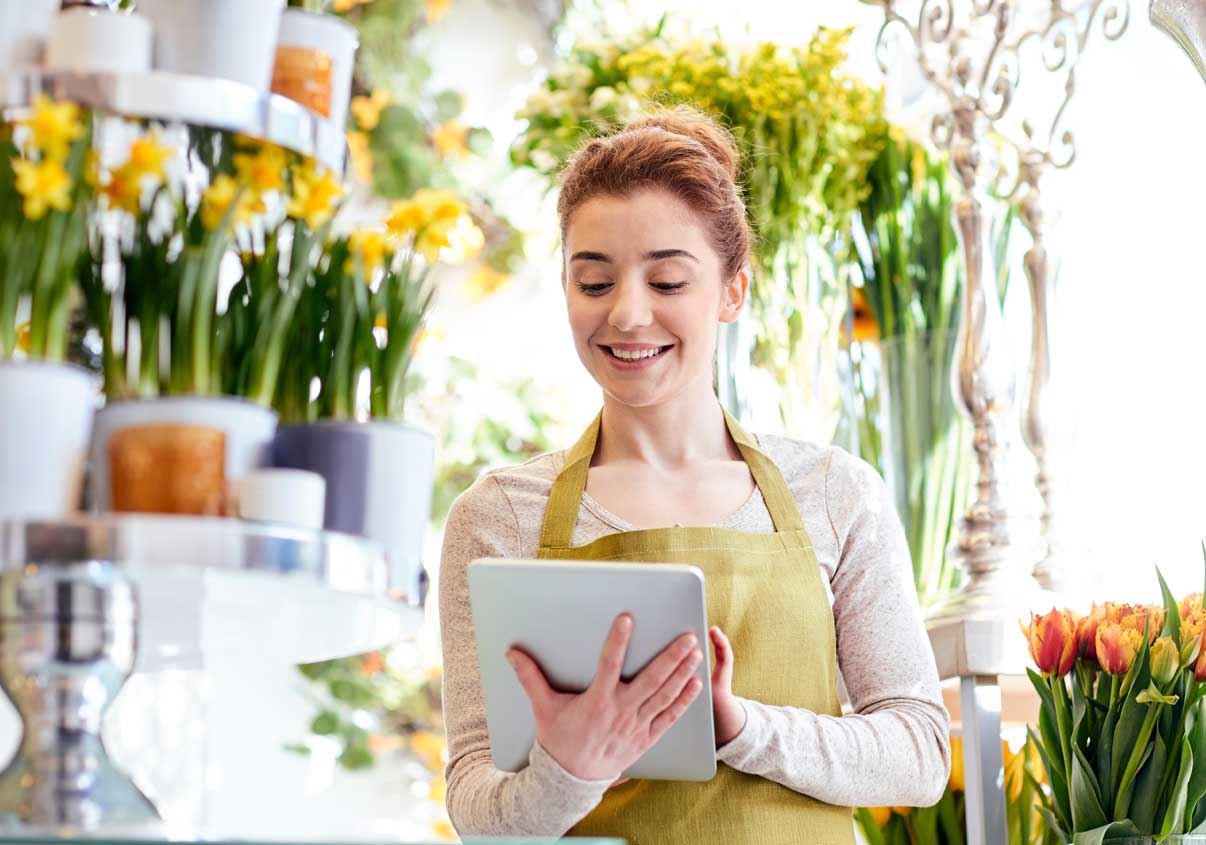 Mulher sorridente mexendo no tablet na floricultura