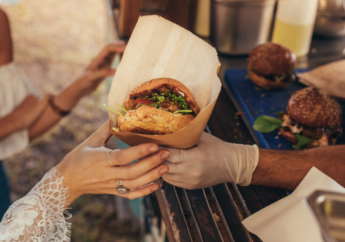 Mulher pegando lanche na mão em um food truck